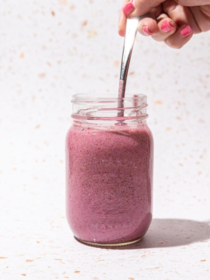 hand stirring raspberry chia pudding with spoon