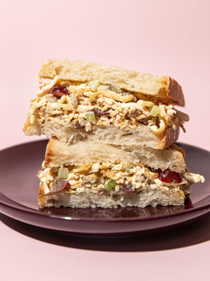 stacked halves of a tofu "chicken" salad sandwich on a purple plate
