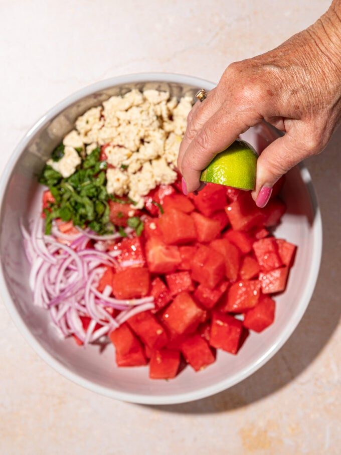 hand squeezing lime over watermelon feta salad
