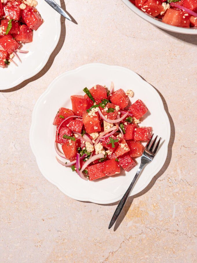 white plates topped with watermelon mint salad with a fork resting beside it