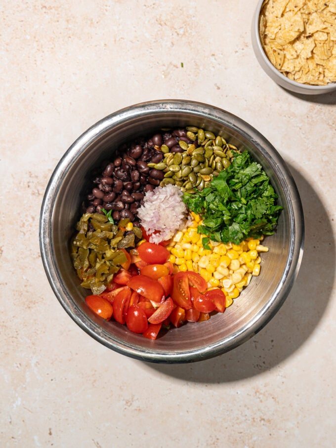 metal salad bowl with black beans, corn, cilantro, pepitas, tomatoes inside