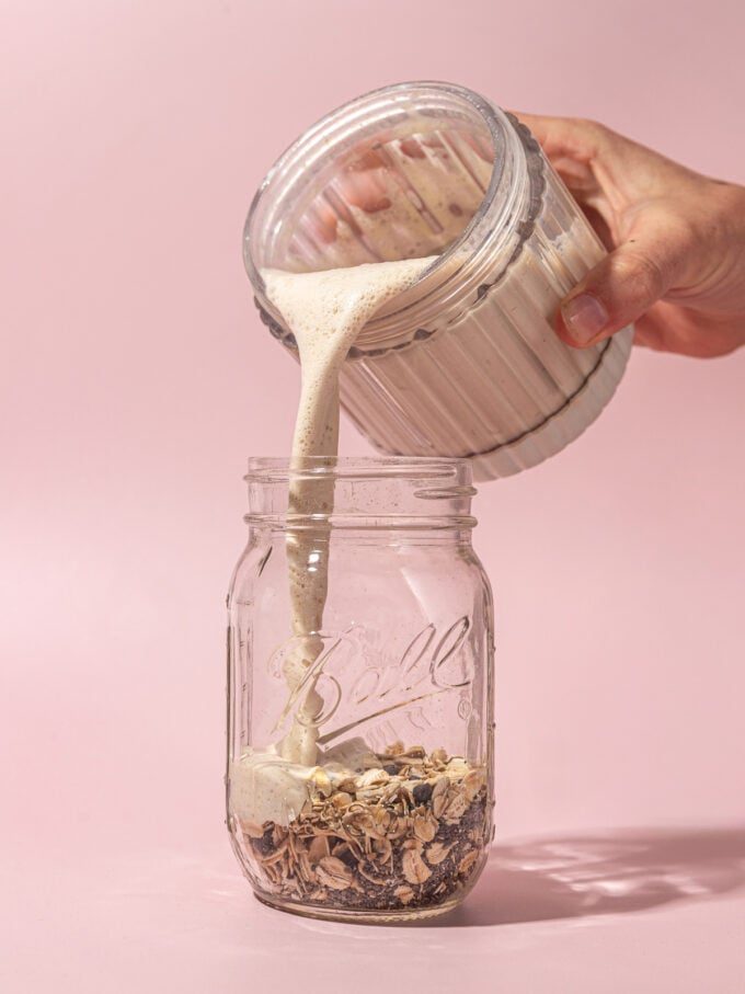hand pouring milk into mason jar with oats, chia and chocolate chips
